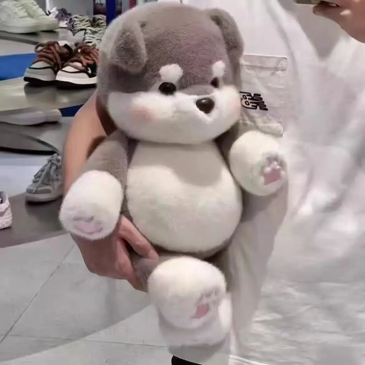 Person holding a plush toy in an indoor setting with shoes in the background