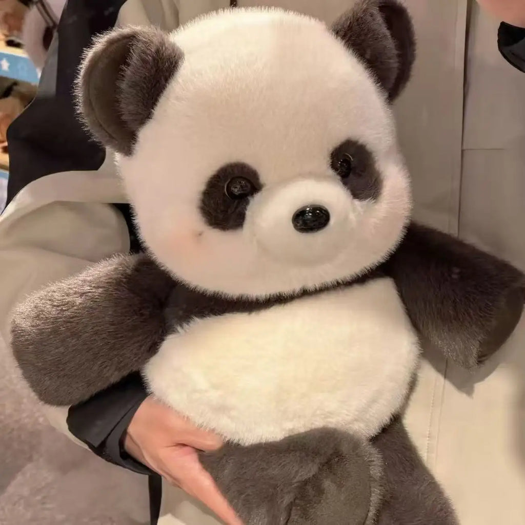 Plush panda toy held by a person with a neutral background