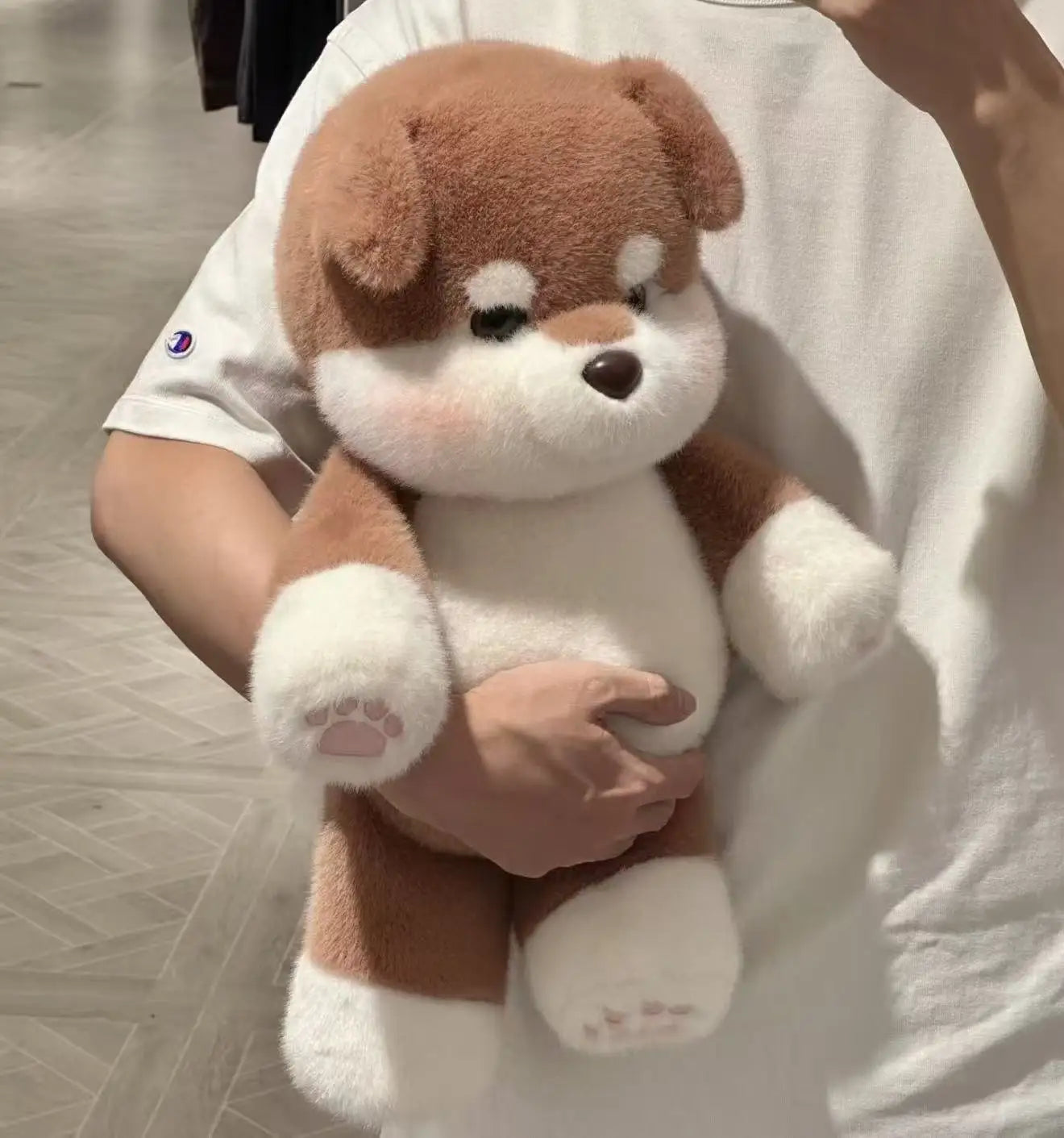 Person holding a brown and white plush dog toy